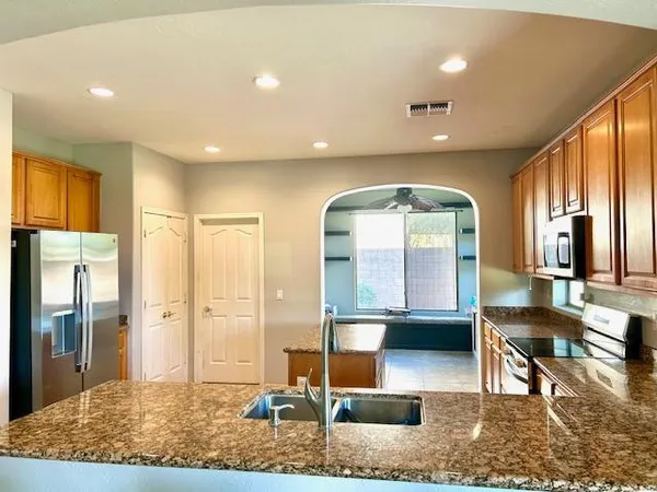 a kitchen with granite countertop a sink a counter top space appliances and cabinets