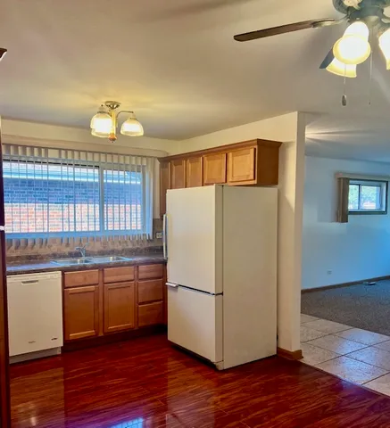 a kitchen with stainless steel appliances granite countertop a refrigerator a sink dishwasher a stove and white countertops with wooden floor