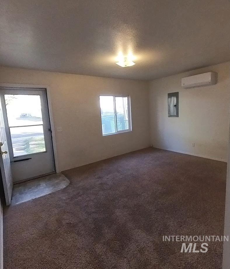418 13th Street Clarkston, WA 99403 - Photo 20 of 26 Unfurnished room featuring dark carpet, a textured ceiling, electric panel, and a wall mounted air conditioner