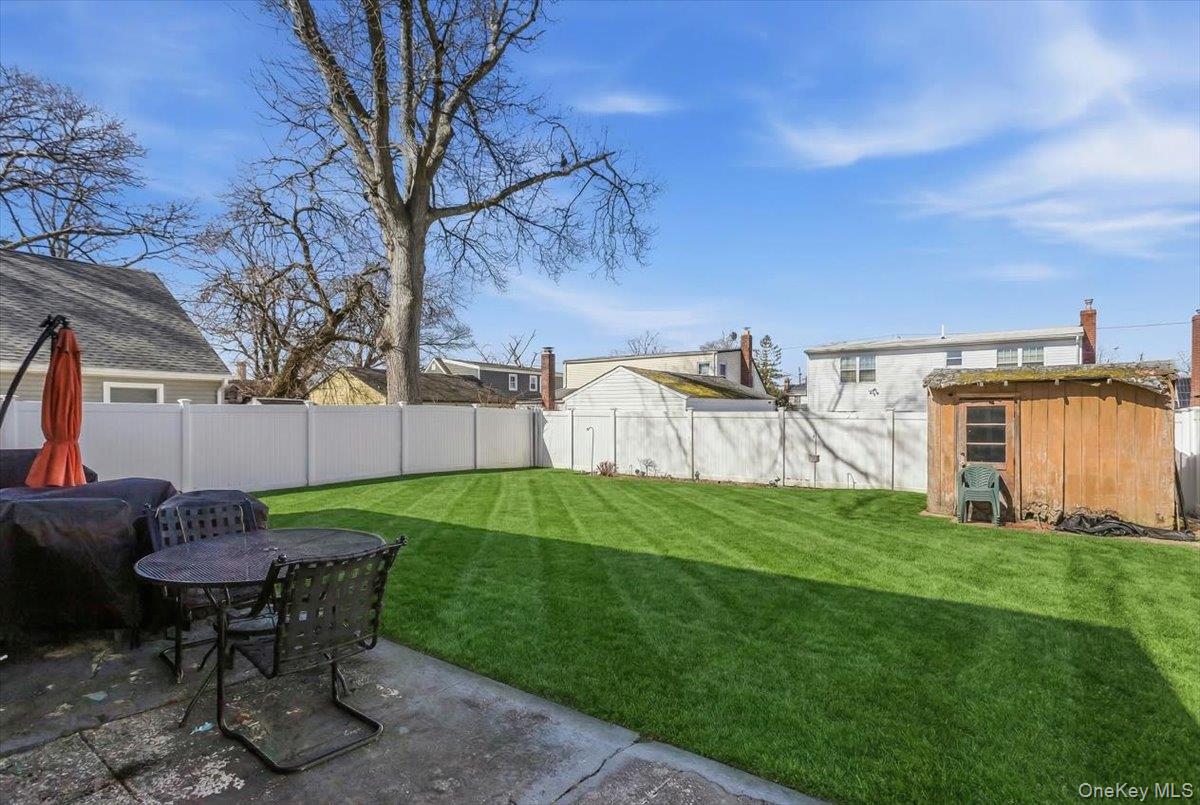 86 Oceanview Avenue Valley Stream, NY 11581 - Photo 20 of 21 a view of a backyard with table and chairs and a fire pit
