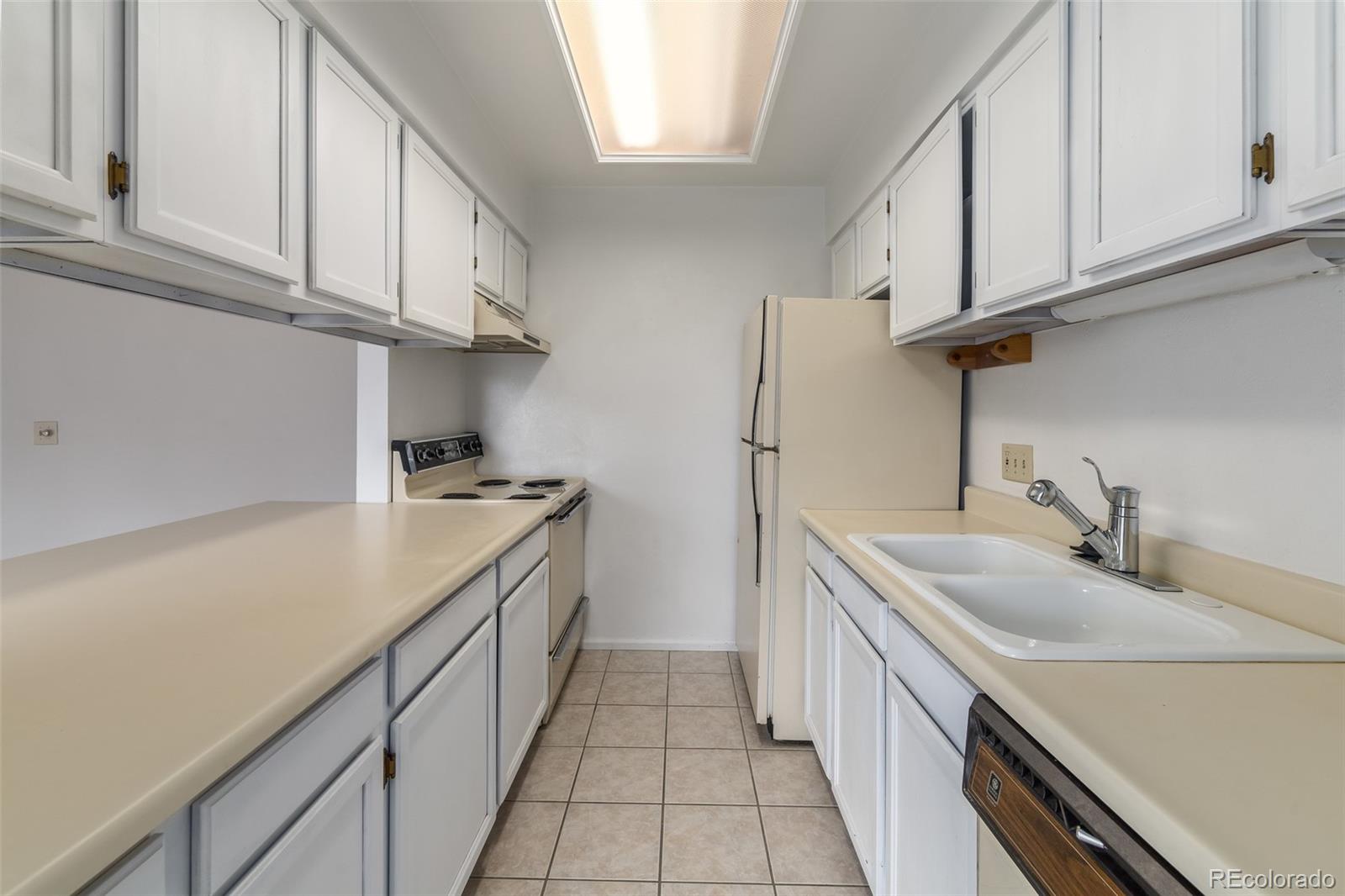8449 Everett Way, Unit E Arvada, CO 80005 - Photo 10 of 25 a kitchen with granite countertop sink dishwasher a stove and a refrigerator with cabinets
