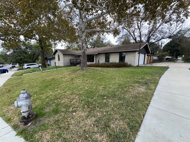 2101 Vanderbilt Lane Austin, TX 78723 - Photo 3 of 11 Ranch-style home with a front lawn, brick siding, driveway, and a chimney