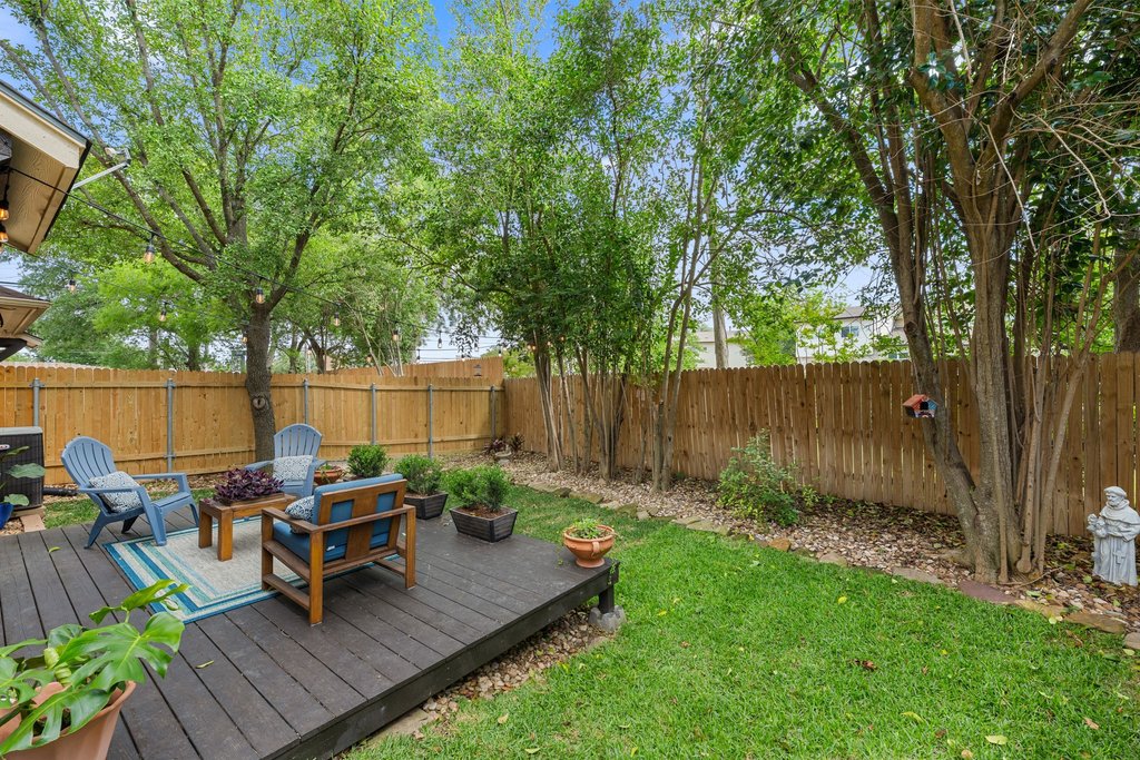 6708 Menchaca Road, Unit 2 Austin, TX 78745 - Photo 30 of 30 Expansive backyard featuring a dark wood-finish deck, lush green lawn, and a natural wood privacy fence
