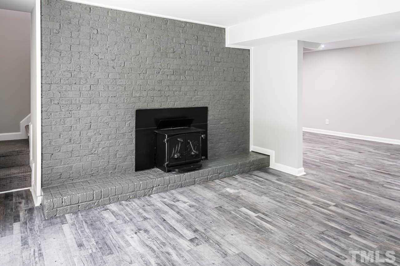3401 Forest Road Raleigh, NC 27604 - Photo 4 of 30 a view of an empty room with wooden floor and a fireplace