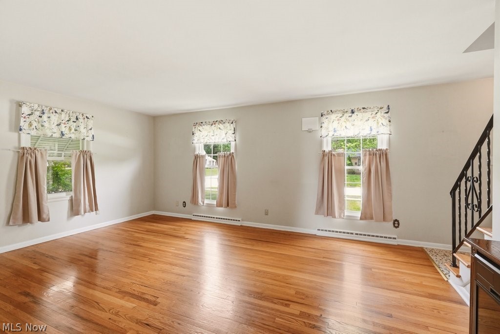 161 Pinehurst Road Munroe Falls, OH 44262 - Photo 8 of 40 Refinished wood flooring in a brightly lit room featuring a staircase with a wrought iron railing