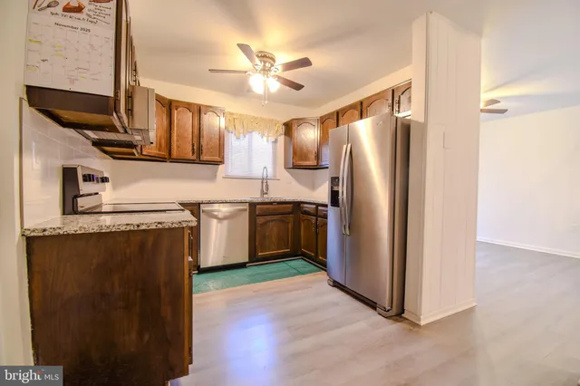 a kitchen with stainless steel appliances granite countertop a refrigerator a sink dishwasher and a stove with wooden floor