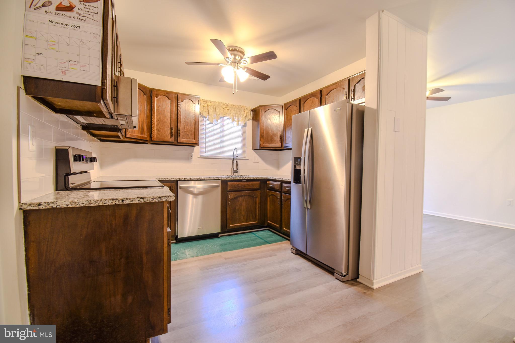 7730 Merrick Lane Landover, MD 20785 - Photo 15 of 19 a kitchen with stainless steel appliances granite countertop a refrigerator a sink dishwasher and a stove with wooden floor