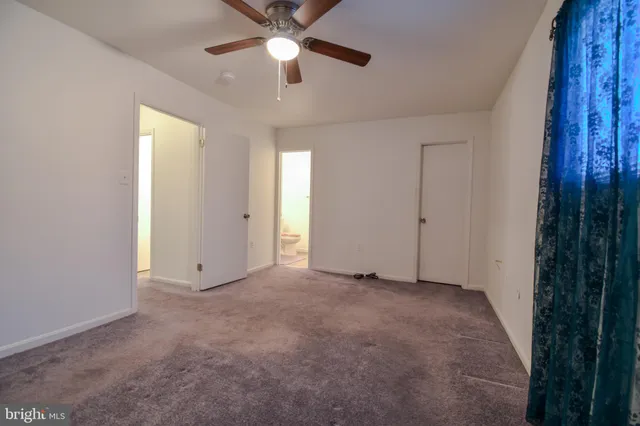 an empty room with chandelier fan and windows