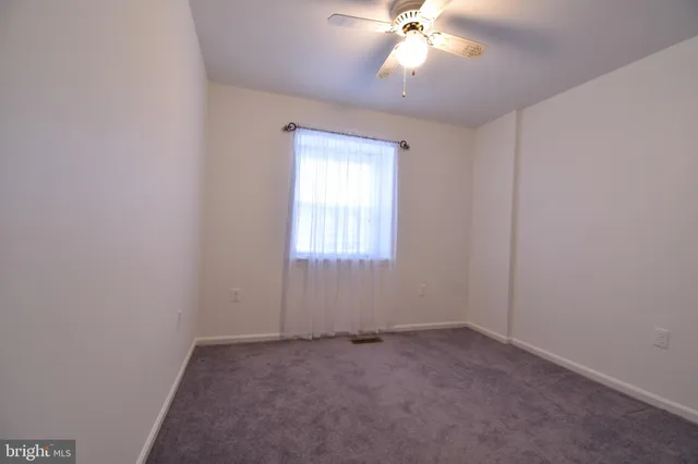 an empty room with a chandelier fan and windows