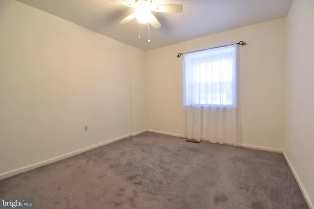 an empty room with a chandelier fan and windows
