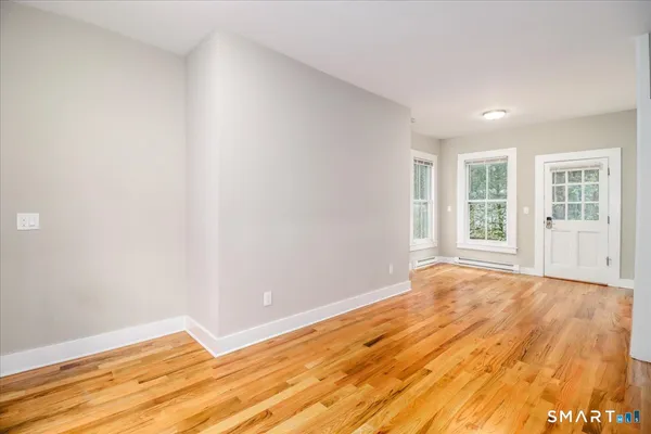 a view of an empty room with wooden floor and a window