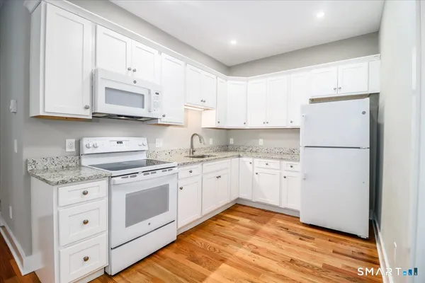 a kitchen with granite countertop white cabinets and white appliances