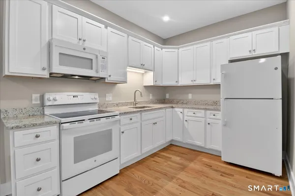 a kitchen with granite countertop white cabinets and white appliances