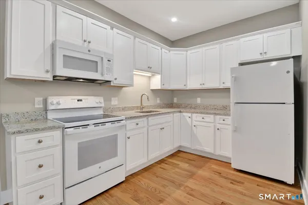 a kitchen with granite countertop white cabinets and white appliances