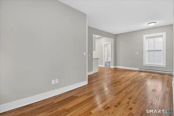a view of an empty room with wooden floor and a window