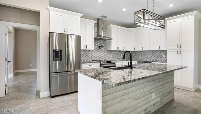 a kitchen with stainless steel appliances granite countertop a refrigerator a sink and white cabinets