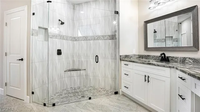 a bathroom with a granite countertop sink a mirror and shower