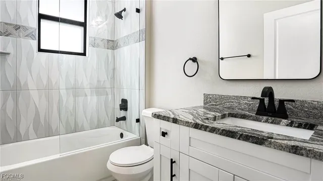 a bathroom with a granite countertop sink mirror toilet and bathtub