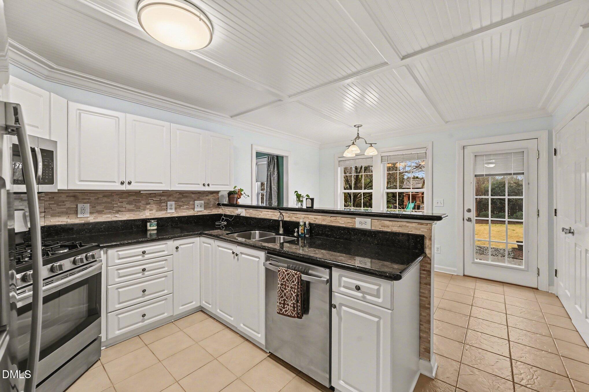 205 Weathervane Way Holly Springs, NC 27540 - Photo 5 of 25 a kitchen with granite countertop a stove sink and cabinets