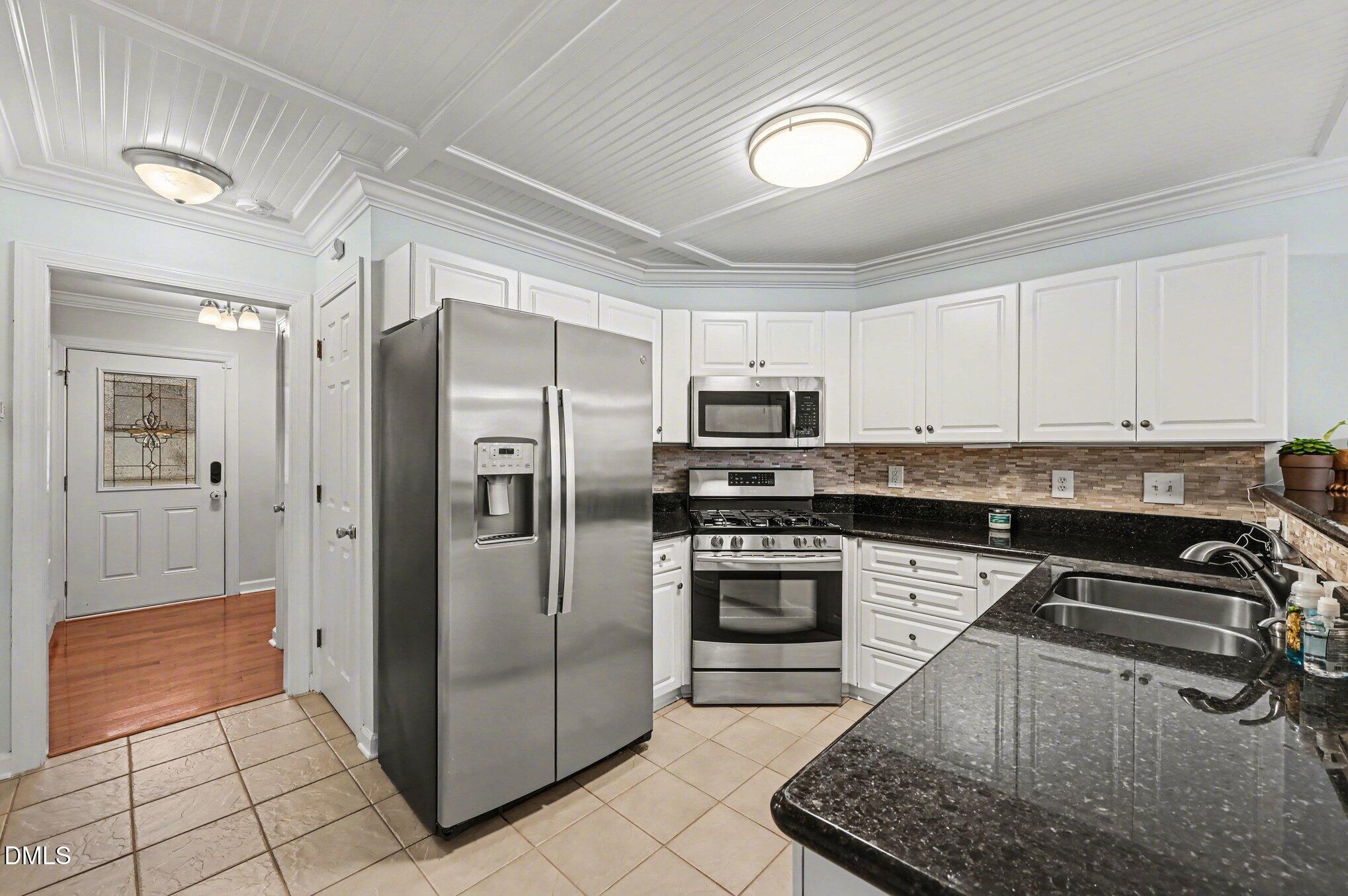 205 Weathervane Way Holly Springs, NC 27540 - Photo 6 of 25 a kitchen with stainless steel appliances granite countertop a refrigerator a stove and white cabinets
