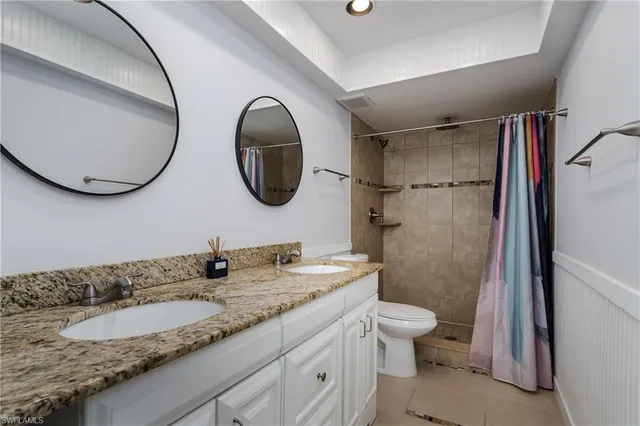 a bathroom with a granite countertop sink mirror toilet and a shower