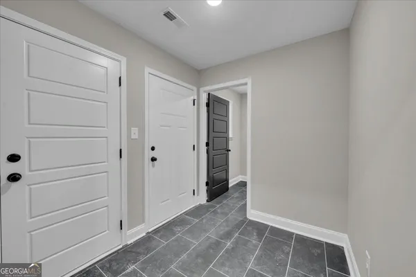 an empty room with windows and fan chandelier