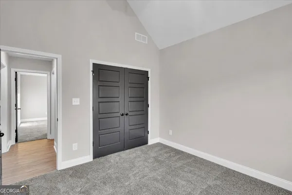 an empty room with chandelier fan and windows