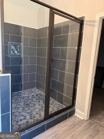 an empty room with wooden floor a ceiling fan a fireplace and windows