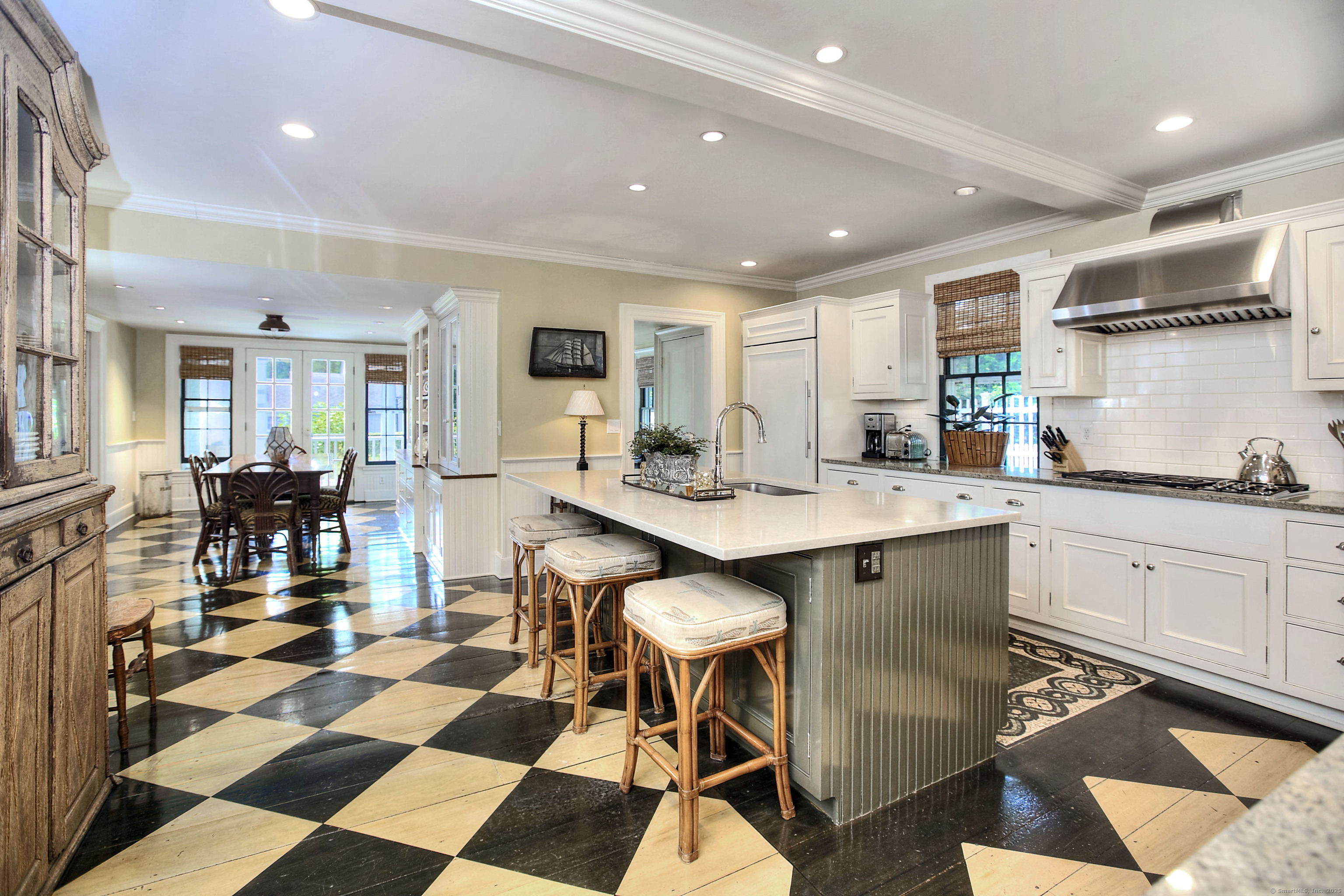 2683 Bronson Road Fairfield, CT 06824 - Photo 15 of 39 a kitchen with a dining table chairs and white cabinets