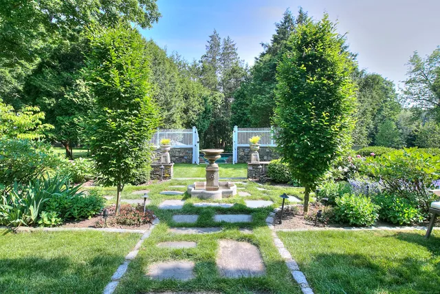 a view of a house with a big yard potted plants and large tree
