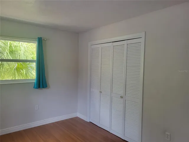 a view of an empty room with wooden floor and windows