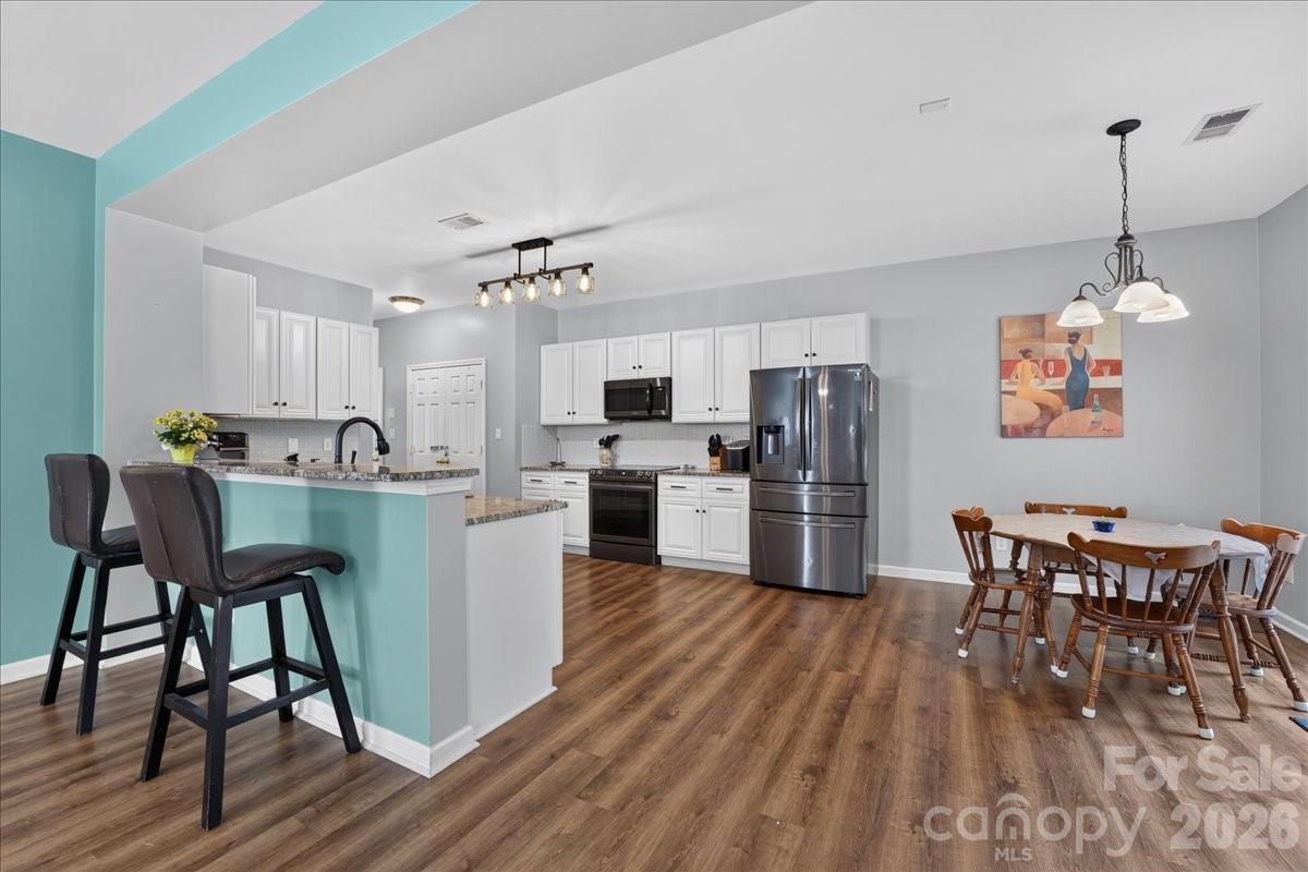 8006 Fine Robe Drive Indian Trail, NC 28079 - Photo 11 of 36 a kitchen with stainless steel appliances granite countertop a dining table chairs refrigerator and sink