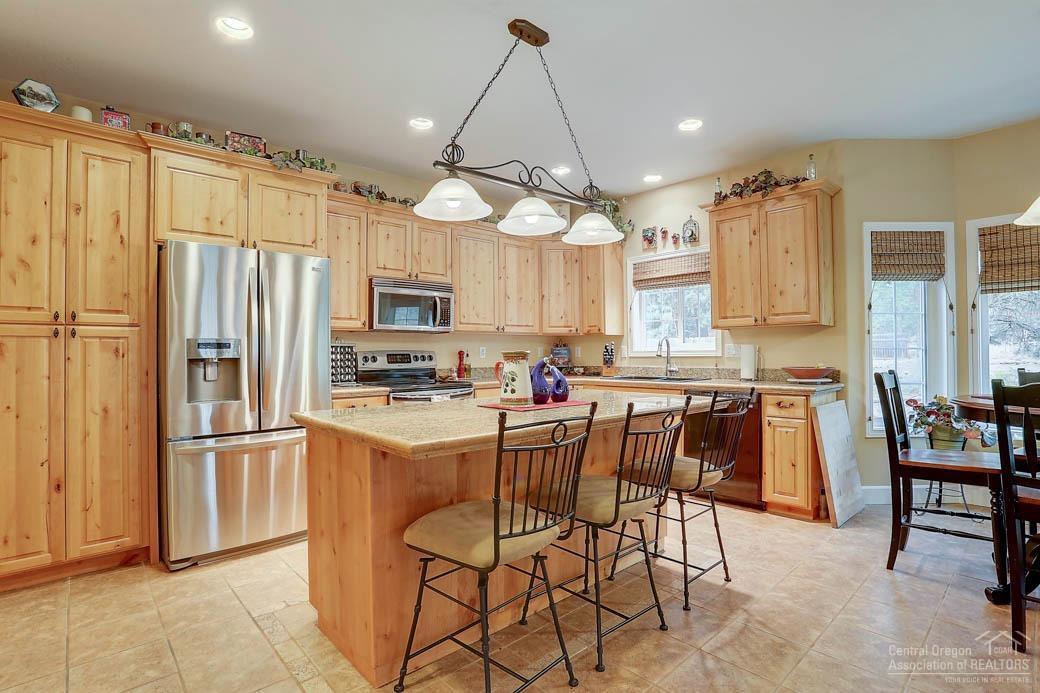 60031 Hopi Road Bend, OR 97702 - Photo 4 of 20 a kitchen with stainless steel appliances kitchen island granite countertop a refrigerator a stove top oven a sink and a dining table with chairs
