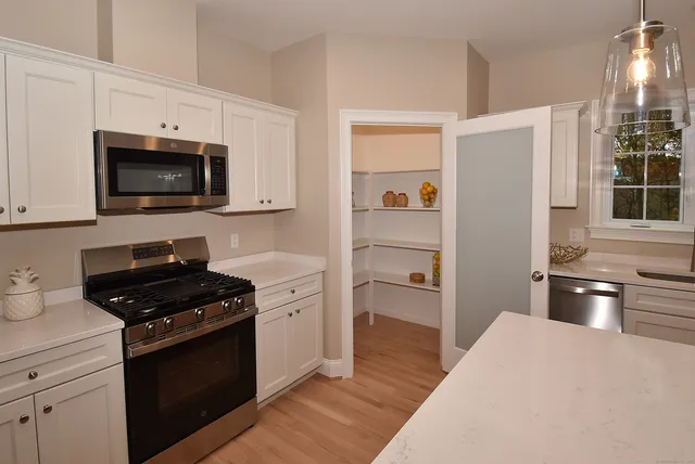 a kitchen with granite countertop a refrigerator and a stove top oven