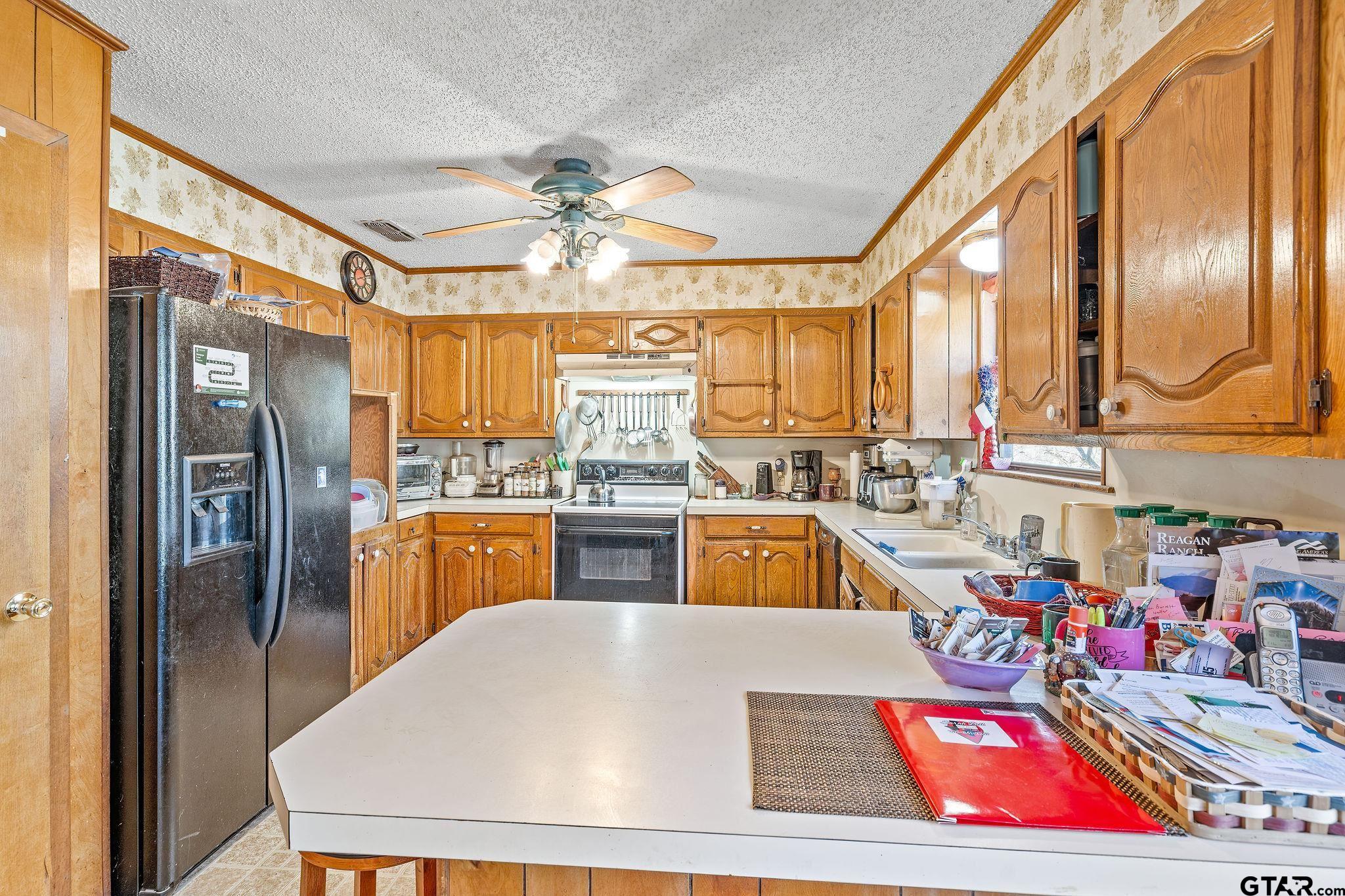 8439 Hyena Road Gilmer, TX 75644 - Photo 4 of 16 a kitchen with stainless steel appliances kitchen island granite countertop a refrigerator a sink and blue cabinets