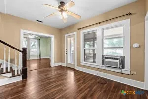 a view of an empty room with wooden floor and a window