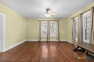 an empty room with wooden floor and windows