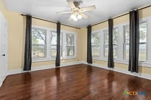 a view of an empty room with window and wooden floor