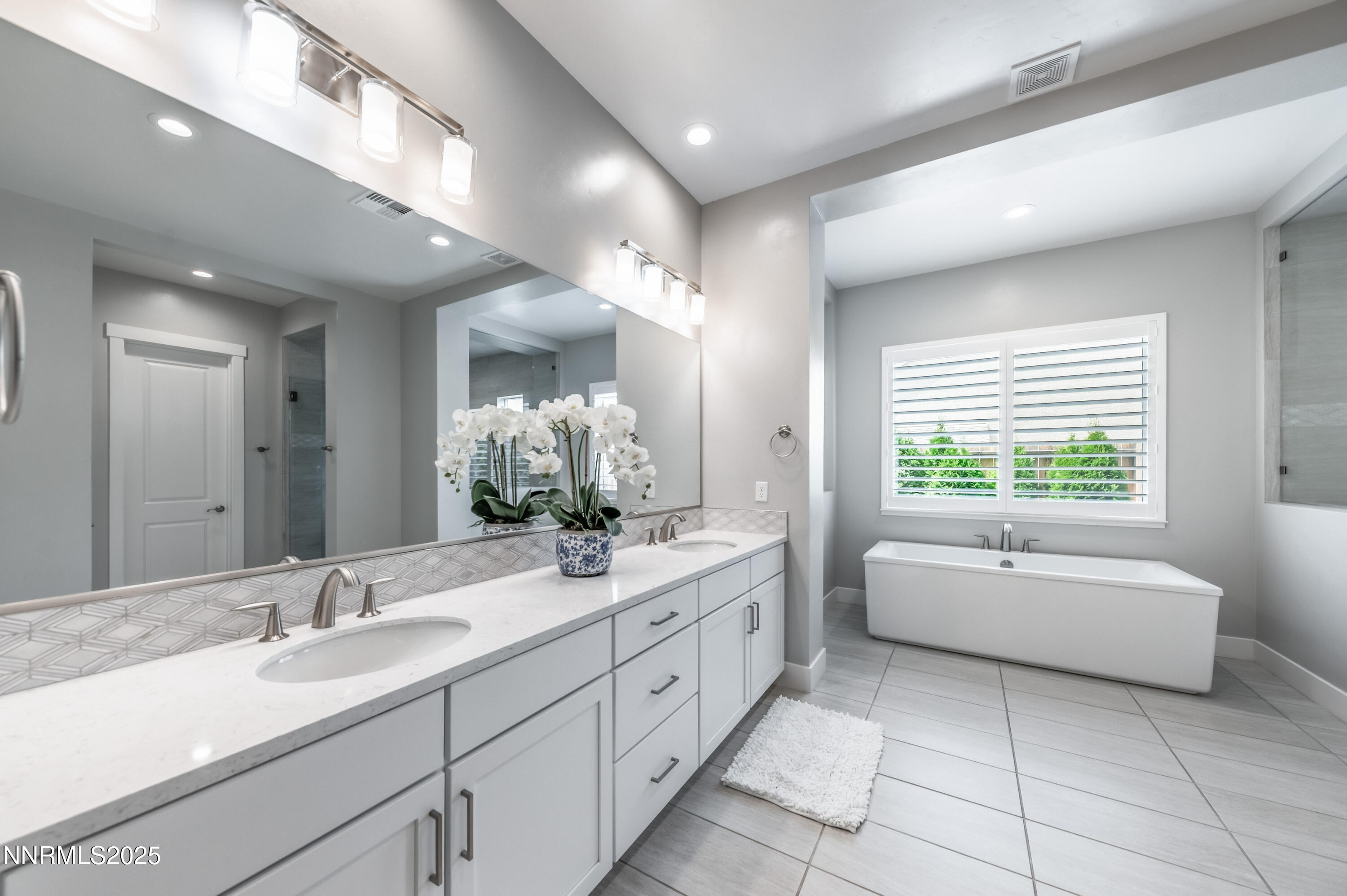 3034 Copper Stone Drive Reno, NV 89521 - Photo 17 of 24 a spacious bathroom with a double vanity sink a large mirror and a bathtub