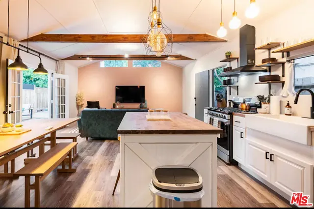 a kitchen with a stove a refrigerator and a dining table with wooden floor