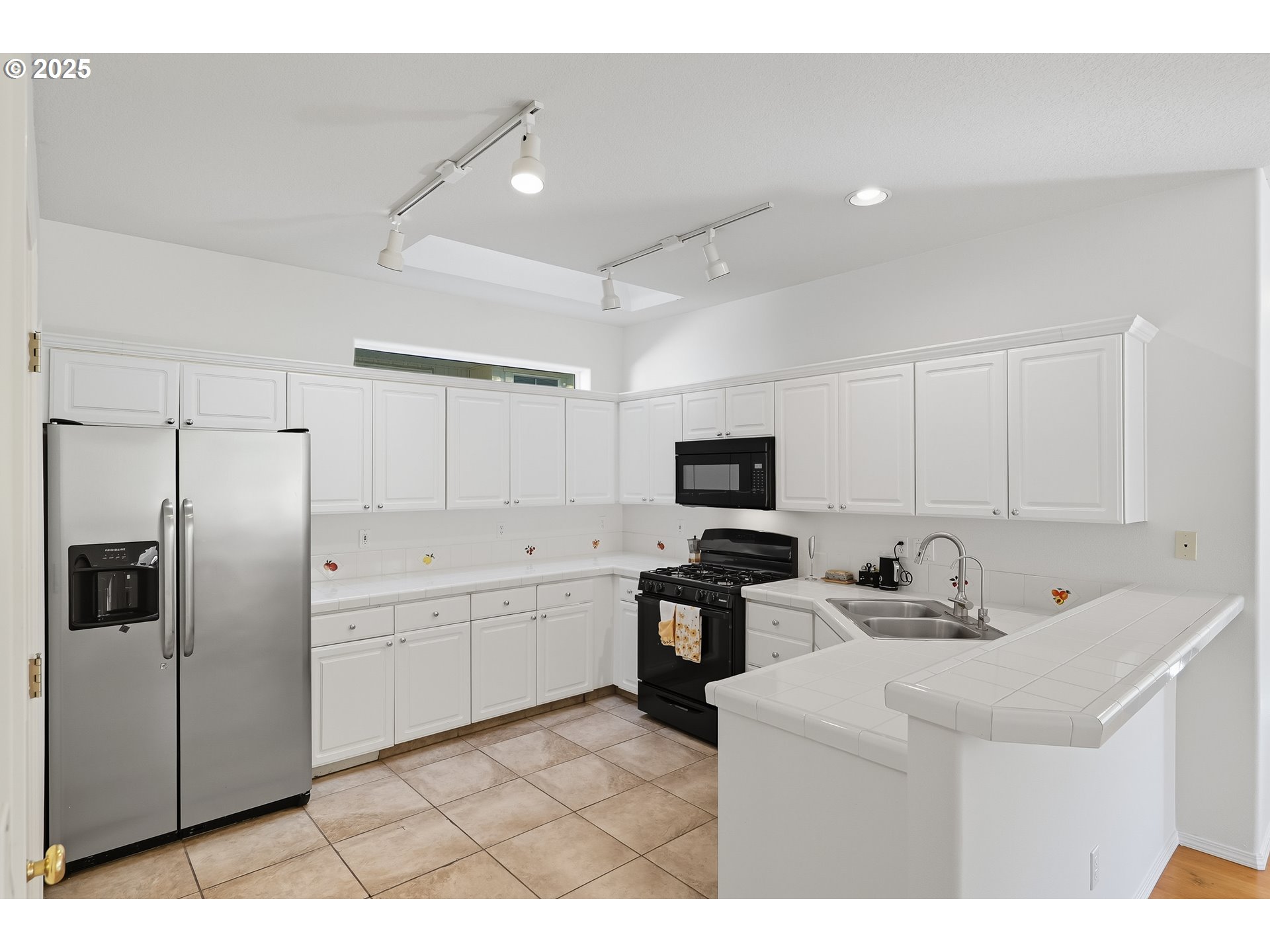 27129 Southwest Aden Avenue Wilsonville, OR 97070 - Photo 12 of 31 a kitchen with stainless steel appliances a stove a sink a refrigerator a microwave a refrigerator and white cabinets