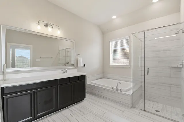 a bathroom with a tub a sink shower and mirror
