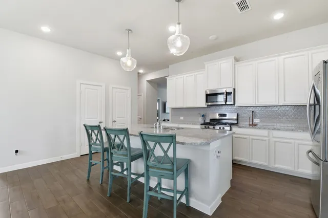 a kitchen with stainless steel appliances granite countertop a white table and chairs