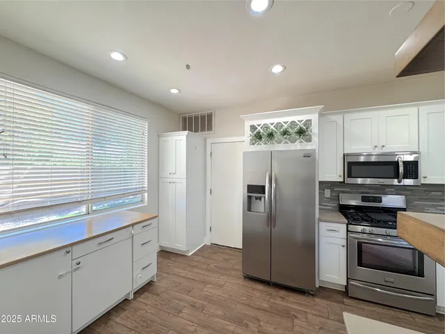 a kitchen with stainless steel appliances granite countertop a refrigerator a stove a sink and a microwave