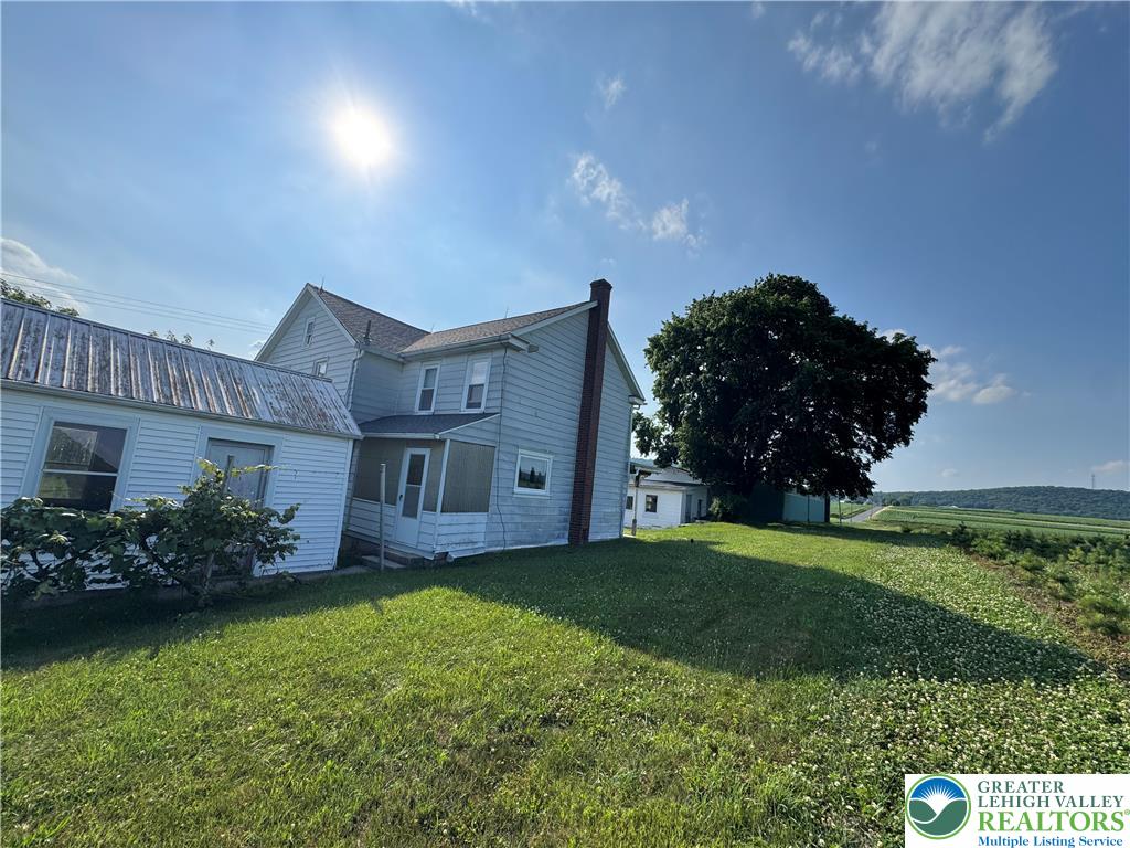 868 Catawissa Road Tamaqua, PA 18252 - Photo 12 of 67 A classic farmhouse exterior with a detached porch, surrounded by lush green landscaping and open fields.
