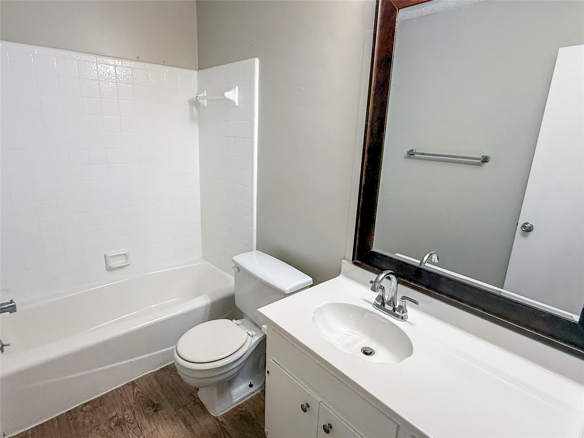 409 Rawhide Loop Round Rock, TX 78681 - Photo 3 of 14 Second bathroom featuring a white bathtub and shower surround, white vanity with integrated sink, chrome faucet, and wood-finish flooring