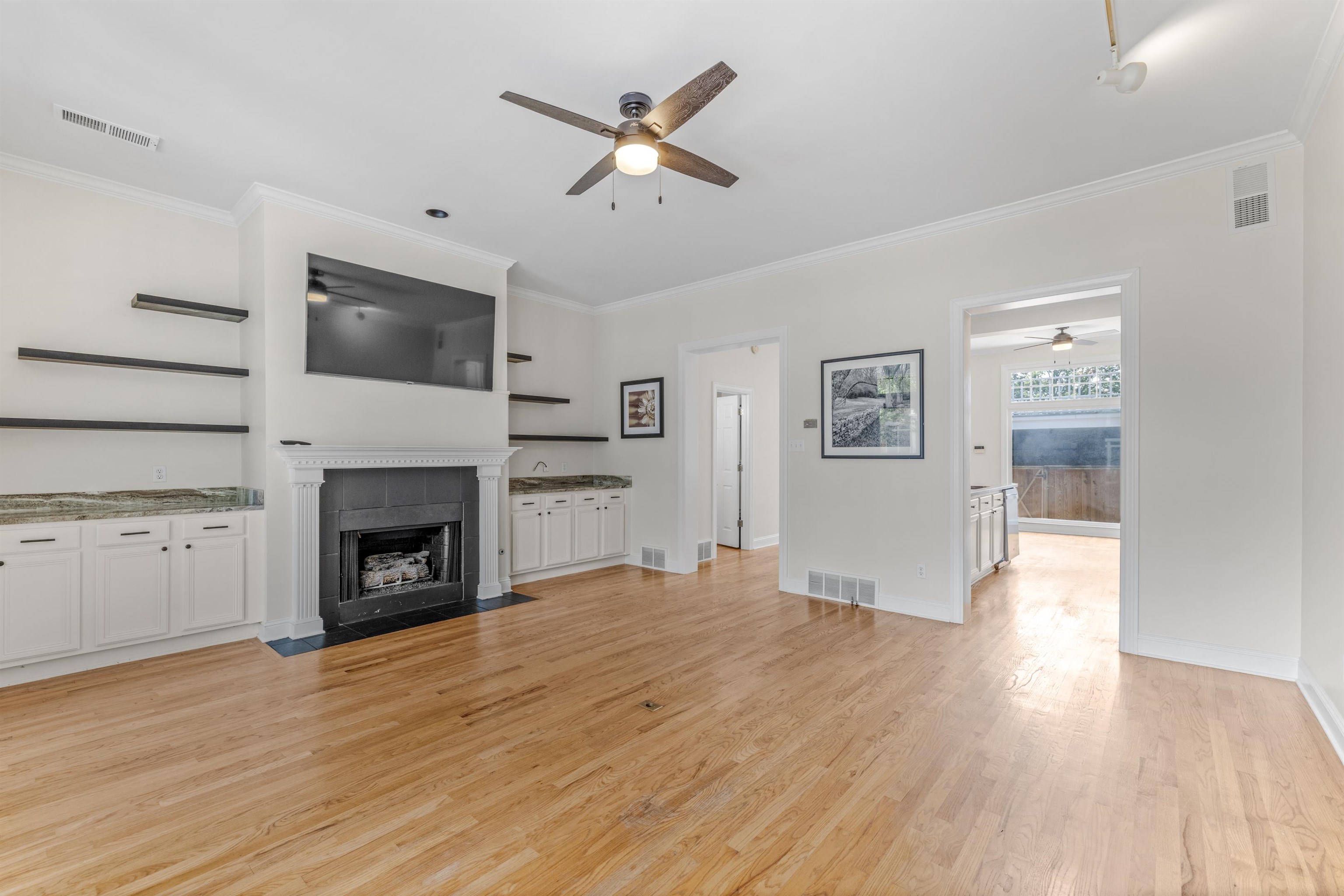 921 Harbor View Drive Memphis, TN 38103 - Photo 3 of 33 Expansive living space featuring hardwood flooring, a fireplace with a mantel, built-in cabinetry with stone countertops, open shelving, and crown molding