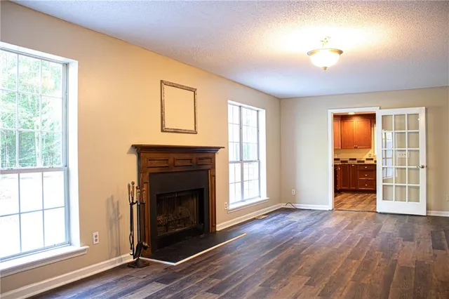 an empty room with wooden floor fireplace and windows