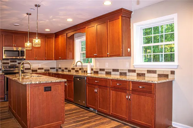 a kitchen with stainless steel appliances granite countertop wooden cabinets a sink and a stove