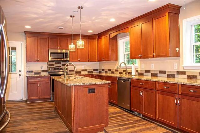 a kitchen with stainless steel appliances granite countertop a stove a sink dishwasher and a refrigerator